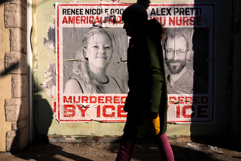 FILE - A woman walks by posters of Renee Good and Alex Pretti during a solidarity bike ride...