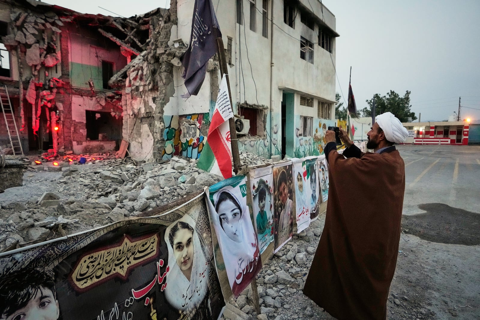 A cleric takes a photograph at the shattered Shajareh Tayyebeh school, which has become a...
