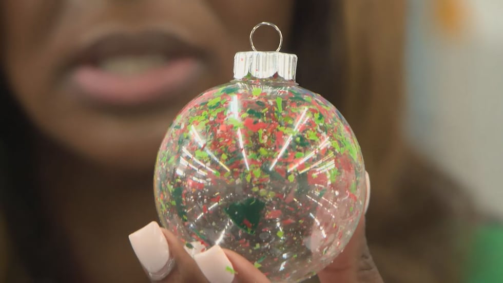 At the ornament table, organizers demonstrate a safe way to make crayon ornaments, showing how...