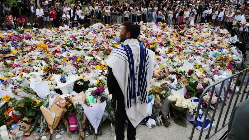 Rabbi Yossi Friedman speaks to people gathering at a flower memorial by the Bondi Pavilion at...