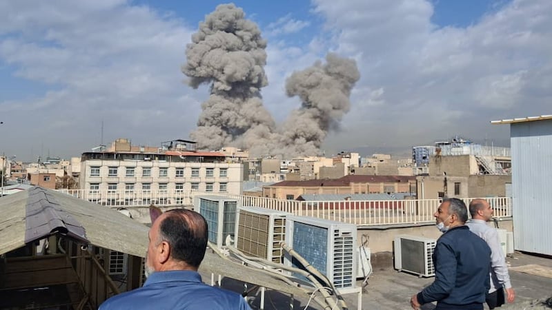 People watch as smoke rises on the skyline after an explosion in Tehran, Iran, Saturday, Feb....