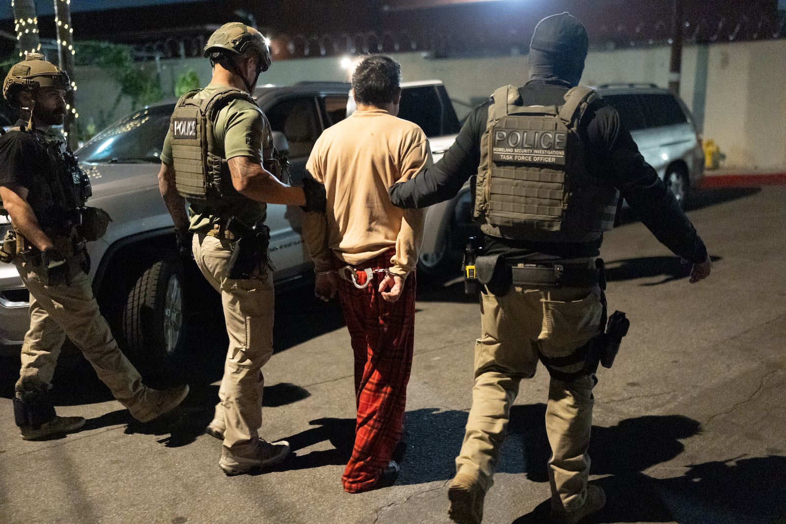 Homeland Security Investigations task force officers escort a suspect accused of illegally...