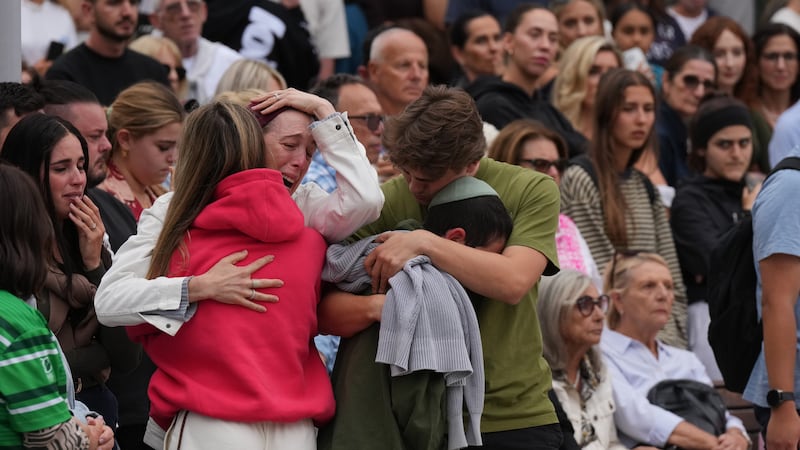 Family members of a victim from Sunday's shooting mourn at a flower memorial made after the...
