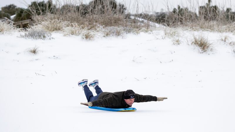 Alex Spiotta, from the Isle of Palms, S.C., uses a boogie board to sled across the beach after...