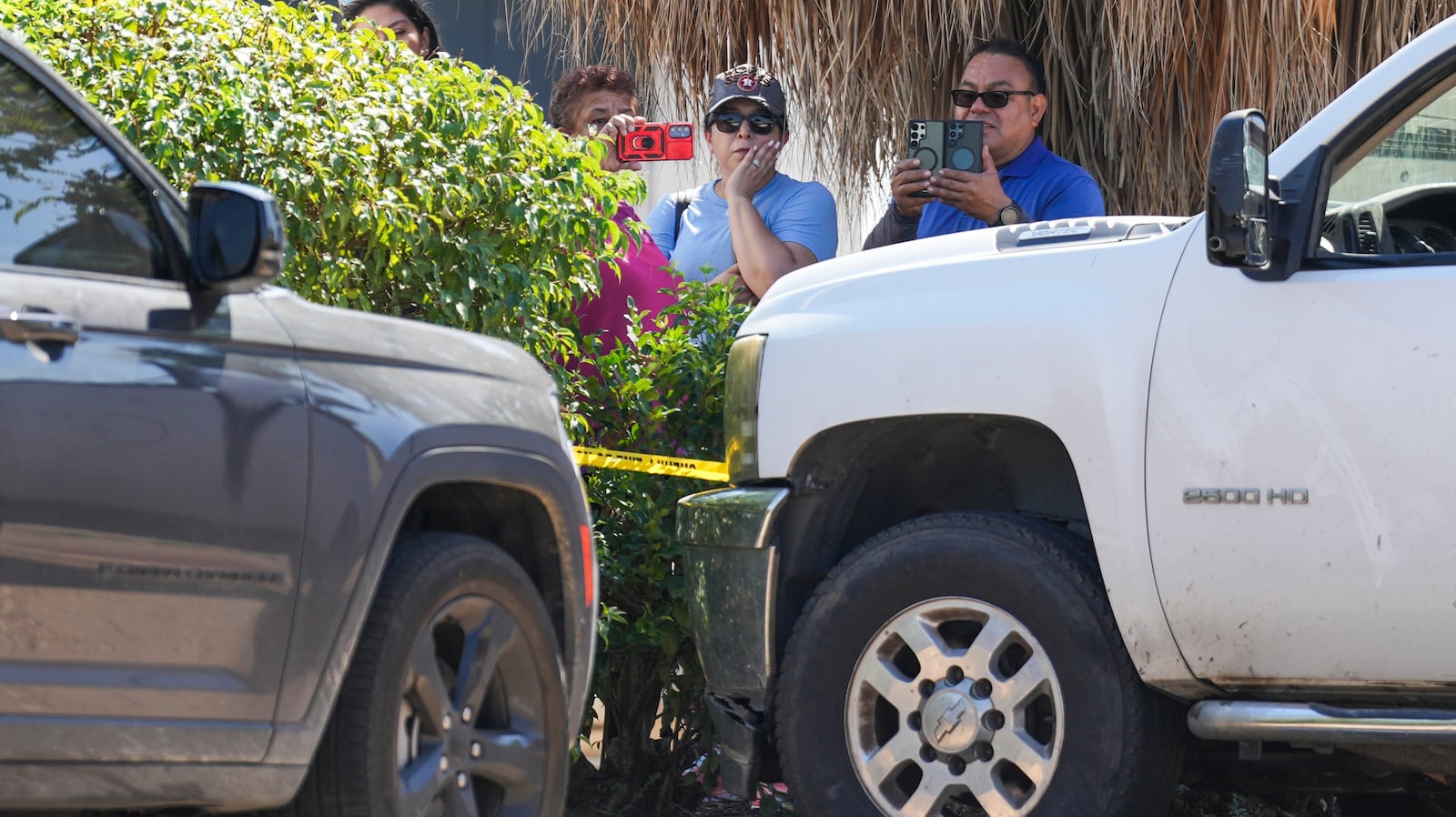 Several people watch as Harris County deputies work at the scene near two vehicles involved...