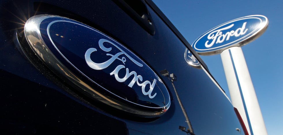 FILE - A Ford logo is on the tailgate of a pick-up truck and on a Ford dealership sign in...
