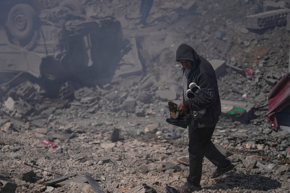 A man carries shoes from his destroyed house that was hit by Israeli airstrikes hit several...