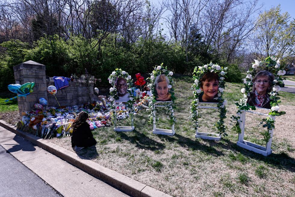 A woman prays near the likeness of four of the victims as she visits a memorial at the...