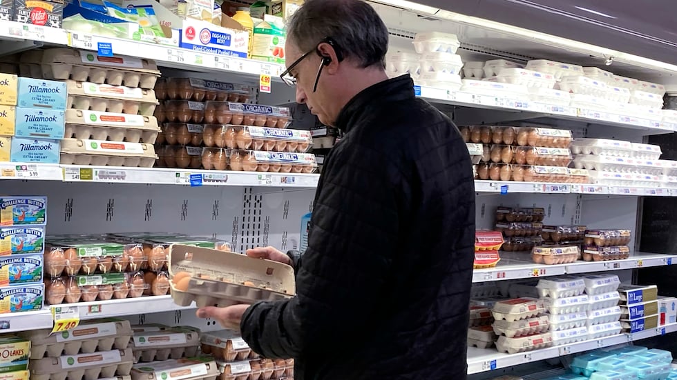 FILE - A shopper checks eggs before he purchases at a grocery store in Glenview, Ill.,...
