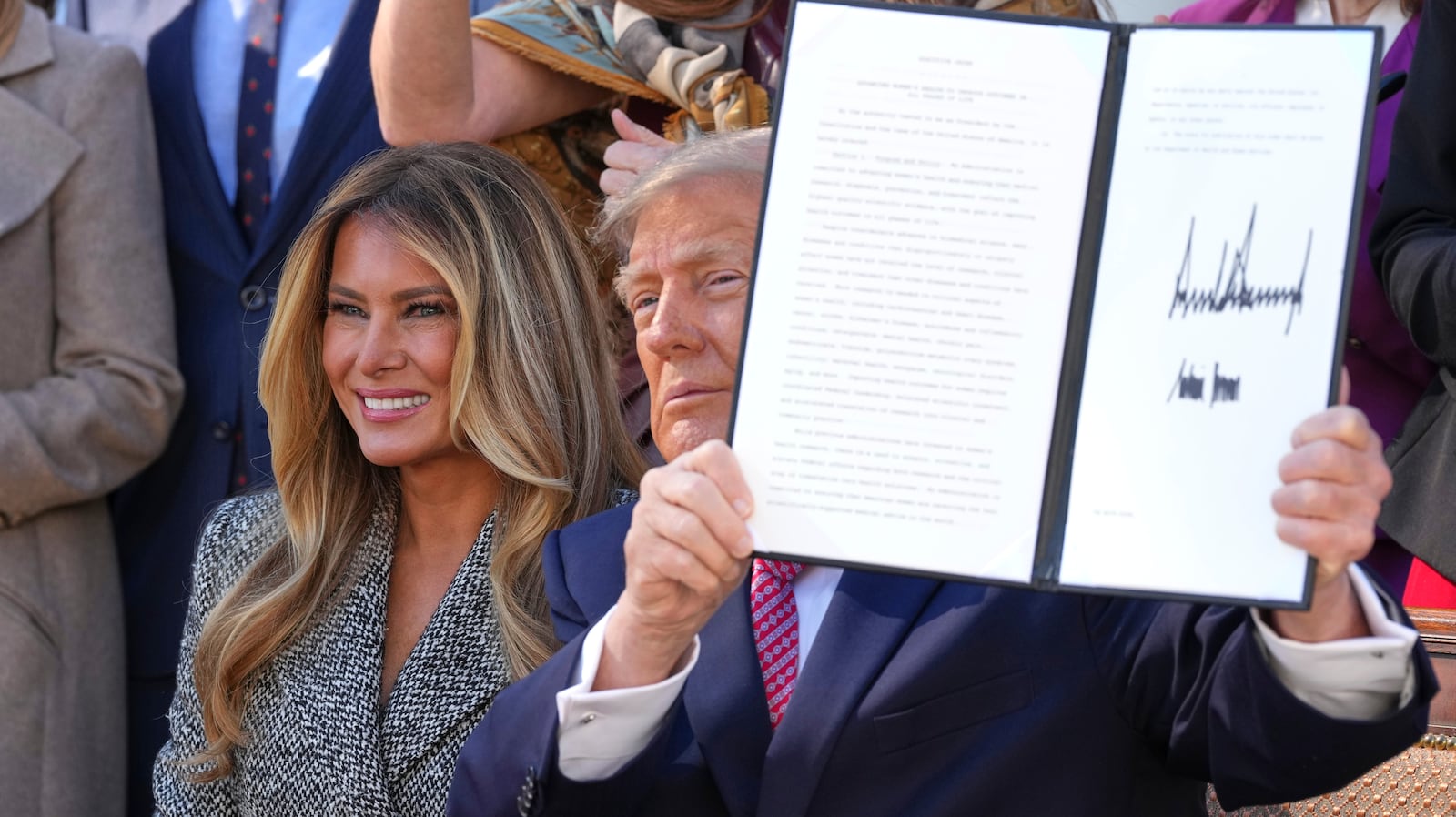 President Donald Trump holds up a signed executive order alongside first lady Melania Trump at...
