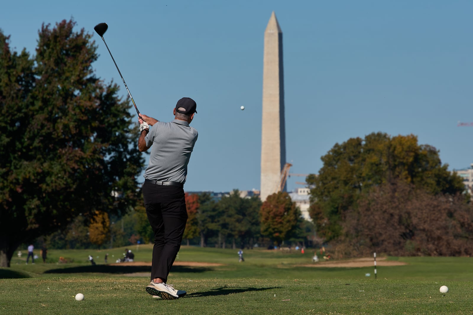 The Washington Monument is seen as a golfer takes a swing at East Potomac Park Golf Course,...